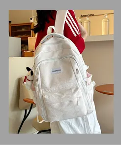 Close-up of white backpack with herringbone texture, featuring a plush dog charm and fabric label