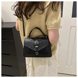 Detailed side view of black crossbody bag with gold U-shaped buckle and leather strap