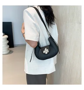 Detail of a black hobo bag featuring a silver metal flower buckle on white blazer