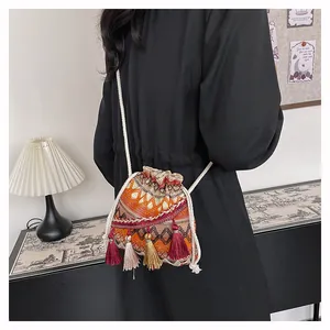 Dettaglio borsa a secchiello etnica con motivo geometrico e nappe colorate
