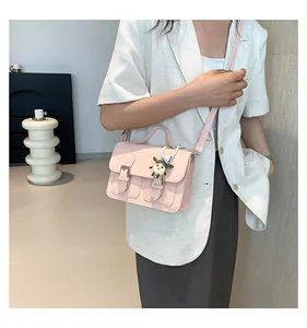 Pink retro crossbody bag with double buckle closure shown on model in white blazer