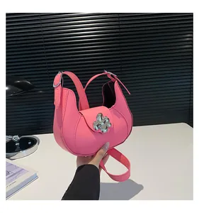 Detail of a pink crescent shoulder bag with a silver metal flower buckle and matte finish