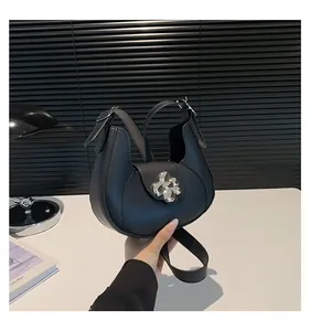 Close-up of black half-moon underarm bag featuring a large silver metal flower buckle