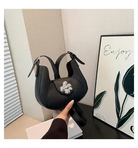 Detailed view of black underarm bag with a large silver floral metal buckle on leather