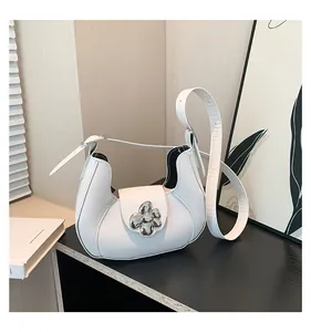 Detail of white half-moon underarm bag featuring a silver metal flower buckle closure