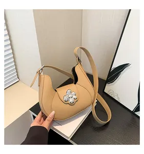 Close-up of beige crescent hobo bag with distinctive silver flower metal buckle detail