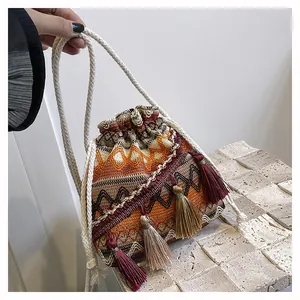 Dettaglio borsa a secchiello boho intrecciata con nappe colorate e tracolla in corda