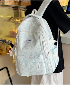 Detail of light blue textured backpack featuring geometric pattern and side straps