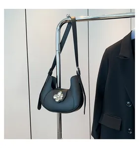 Close-up of black leather half-moon underarm bag with elegant silver flower buckle