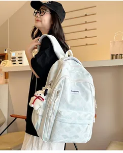 Close-up of light blue textured backpack with white plush puppy charm and front logo