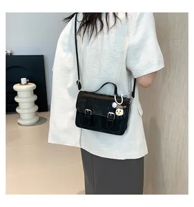 Model view of black vintage crossbody bag with silver buckles and cute doll charm