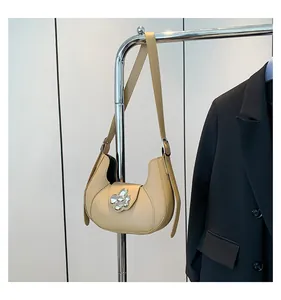 Detailed view of beige half-moon bag with crystal flower buckle on metal hanger