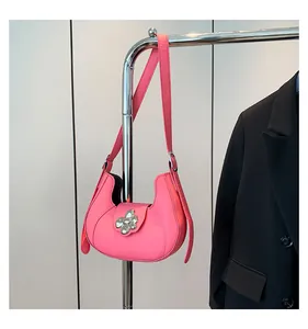 Detail of pink underarm bag featuring a silver metal flower buckle and leather strap