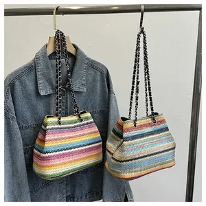Détail de sacs cabas en paille rayés avec bandoulières en chaîne métallique et cuir