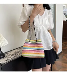 Détail d'un sac tressé aux rayures arc-en-ciel avec une bandoulière en chaîne argentée chic