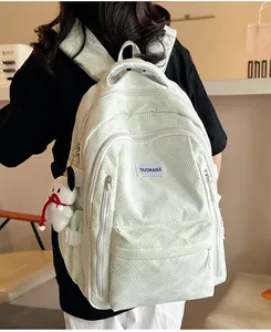 Detailed back view of mint green textured backpack with cute white puppy plush charm