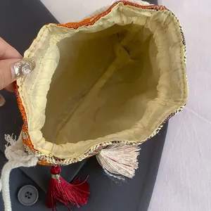 Borsa a secchiello tessuta in stile etnico con motivi arancioni e dettagli di nappe