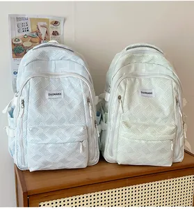 Close-up of woven fabric texture and branding detail on pastel blue and green backpacks