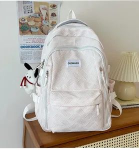 Detail of white embossed backpack with geometric pattern, brand tag and plush charm