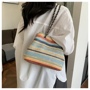 Détail du sac en paille à rayures multicolores avec chaîne métallique et bandoulière en cuir