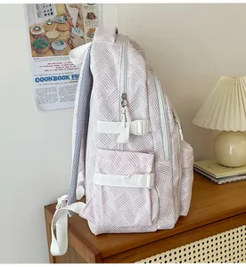 Detail view of pink backpack with quilted pattern and side buckle on wooden table