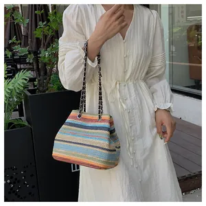 Détail d'un sac bandoulière tissé à rayures colorées avec bandoulière en chaîne