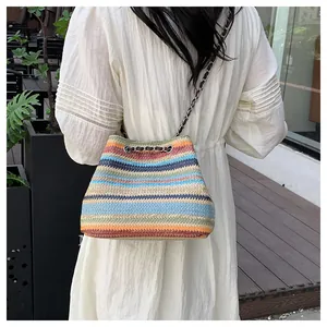 Détail du sac seau en paille à rayures colorées avec bandoulière en chaîne dorée