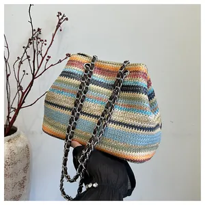 Détail du sac bandoulière en paille à rayures colorées avec chaîne et lanières brunes