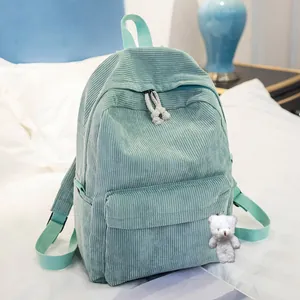 Detail view of corduroy backpack texture with mint green fabric and plush bear charm