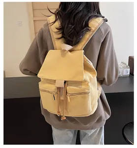 Detalle de mochila tipo cubo en lona amarilla con cordón y bolsillos frontales con cremallera
