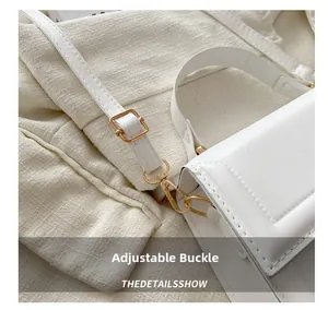 Detail of adjustable metal buckle and strap on a white leather shoulder bag