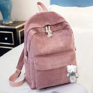 Detailed close-up of pink corduroy backpack with cute bear plush and white knotted zipper