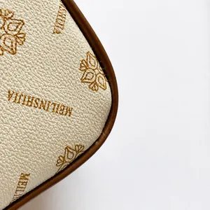 Macro shot of grainy cream leather featuring vintage floral monogram and brand lettering