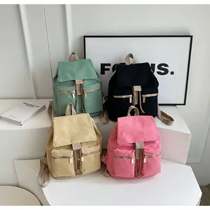 Detalle de mochilas de lona retro en colores menta, negro, caqui y rosa suave