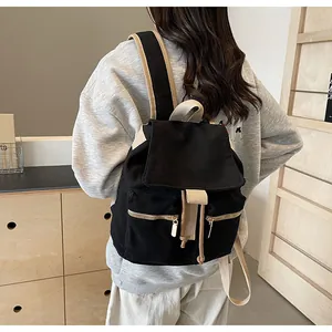Detalle de correas beige y cremalleras metálicas en mochila de lona negra tipo cubeta
