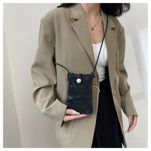 Dettaglio mini borsa nera a tracolla con chiusura a perla e raffinata trama a pieghe
