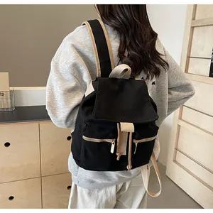 Vista trasera de mochila de lona negra con detalles beige llevada por una modelo