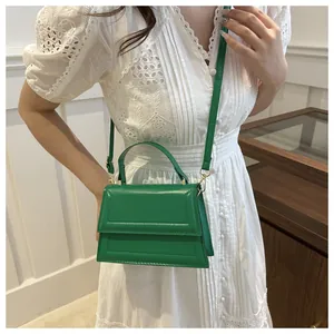 Detail of green glossy crossbody bag featuring quilted design and gold-tone hardware