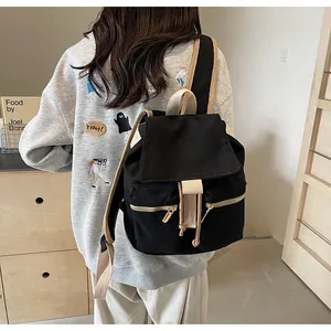 Detalle de una mochila tipo cubo de lona negra vintage con correas beige y cordón
