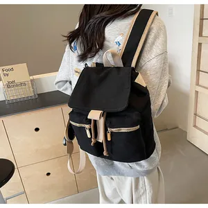 Detalle de una mochila tipo cubo de lona negra con correas beige y bolsillos con cremallera
