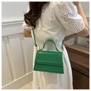 Street style grass green shoulder bag with top handle and gold hardware on white dress