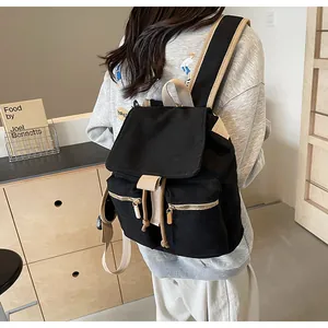 Detalle de mochila tipo saco en lona negra con correas beige y cremalleras metálicas