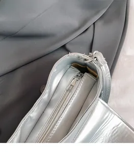 Macro detail of the smooth silver metallic zipper and hardware on the baguette shoulder bag