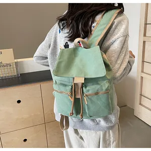 Vista detallada de mochila de lona verde claro con cremalleras y correas de tela