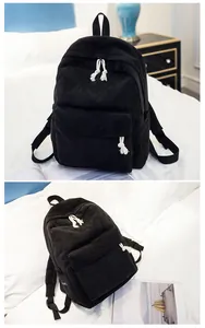 Detail of black corduroy backpack with white rope zippers and adjustable shoulder straps