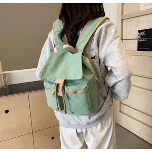 Detalle de la mochila de lona verde menta con cordón y cremalleras doradas
