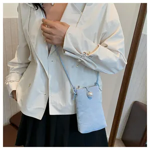Mini borsa a tracolla azzurra con bottone a perla indossata con blazer color crema
