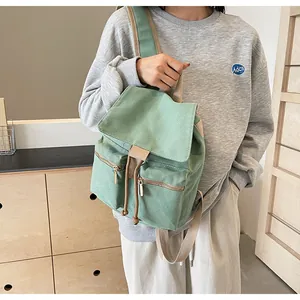 Detalle de la mochila de lona verde menta con cierre de cordón y bolsillos con cremallera