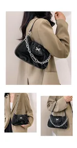 Detail of black faux leather shoulder bag featuring marble texture and silver butterfly buckle