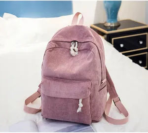 Detailed close-up of pink corduroy backpack fabric with zip pockets and side bottle holder
